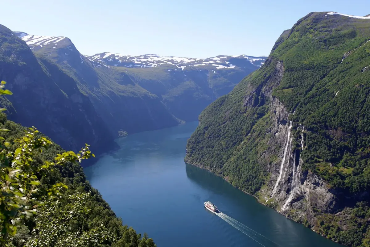 A coastal ship sailing the Geirangerfjord below the Seven Sisters waterfalls