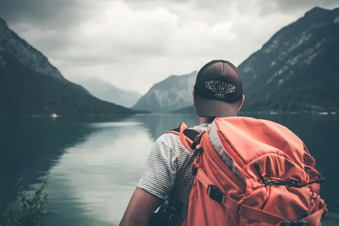 Traveller with a backpack at an alpine lake