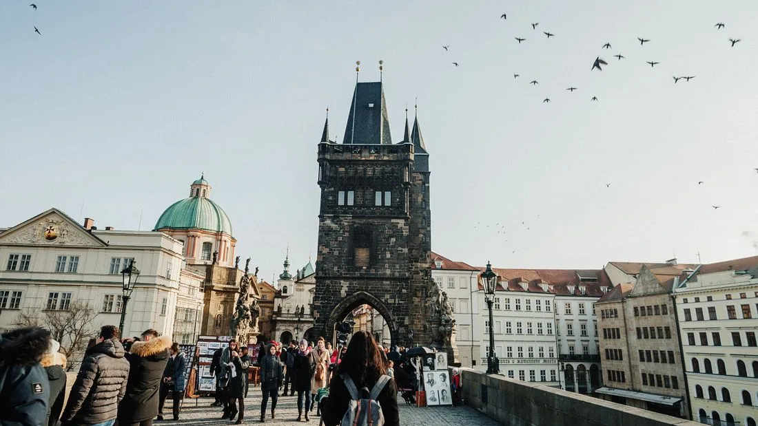 Visitors crossing Charles Bridge beneath the Old Town bridge tower, Prague