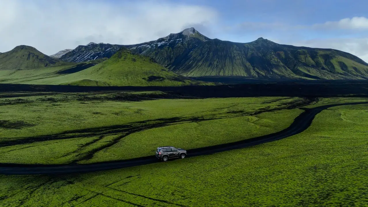 A road through a green valley below mountains in Iceland