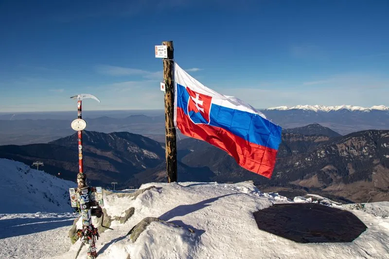 A summit marker and the Slovak flag on a peak in the High Tatras